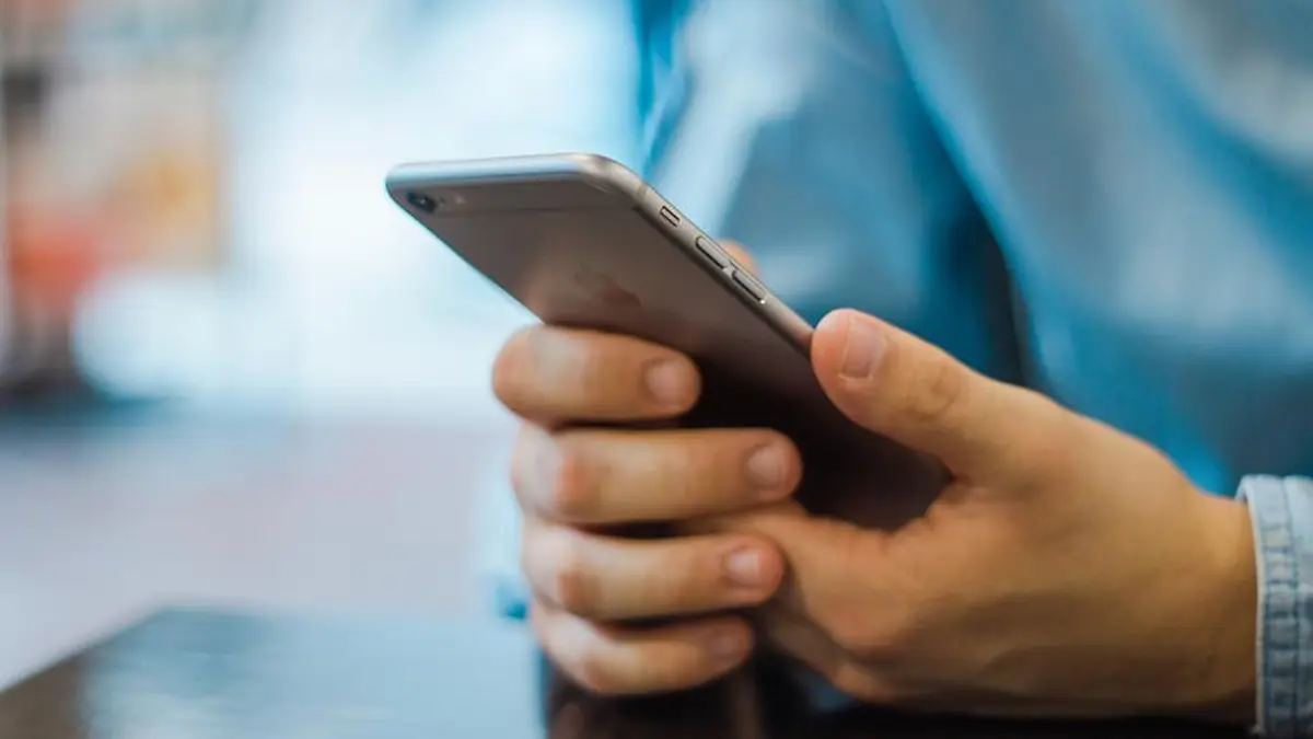 Mãos segurando um celular, conversando por mensagem