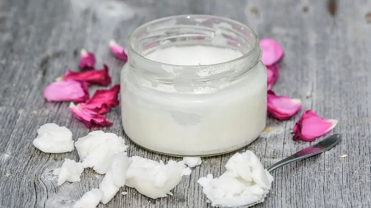Pote de vidro com iogurte de coco e pedaços de coco ao redor