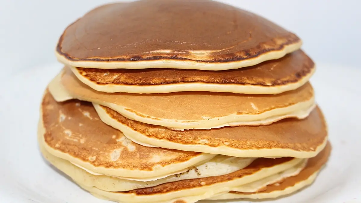 Pilha de panquecas douradas num prato branco